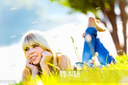 Enjoying sun teen girl is lying on the grass