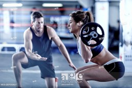 Trainer watching woman doing fitness training with weights