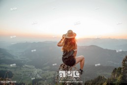 Switzerland, Grosser Mythen, young woman on a hiking trip sitting on a rock at sunrise