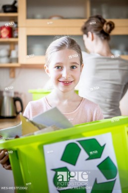 Portrait of smiling girl at home holding waste box