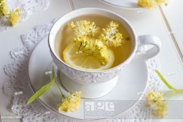 A cup of herbal tea with fresh linden flowers and lemon