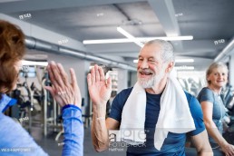 Happy senior man and woman high fiving after working out in gym